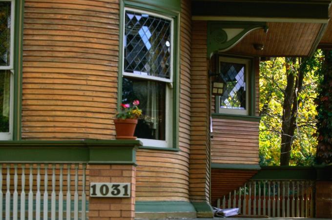 Detalje af afrundet hus veranda, naturligt træ sidespor med grønne trim, dobbelt hængt blyindvinduer, dekorative corbels