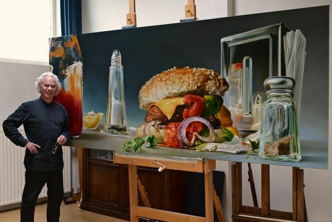 Mand står med et stort billede af en hamburger og salt og peber ryster.