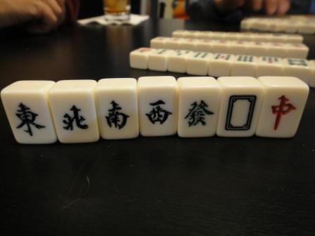 Vindene og dragerne fliser i et Mahjong-sæt, der står lodret på et bord.