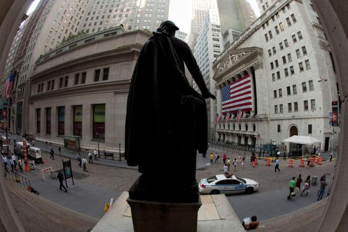 Bag et stort amerikansk flag, der dækker kolonnaden, overvåges New York Stock Exchange-facaden af ​​en statue af George Washington på Wall Street.