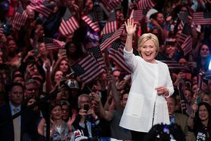 Hillary Clinton bølger foran mængden af ​​mennesker, der vifter med amerikanske flag