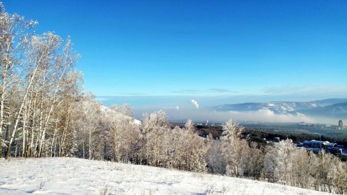 Naturskøn udsigt over snedækket landskab mod blå himmel