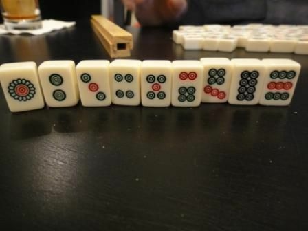 Stenen passer til et standard sæt Mahjong-fliser, der står op på et bord.