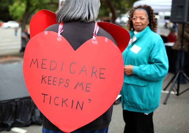 Kvinde iført et hjerteformet skilt med teksten 'Medicare Keeps Me Ticking'