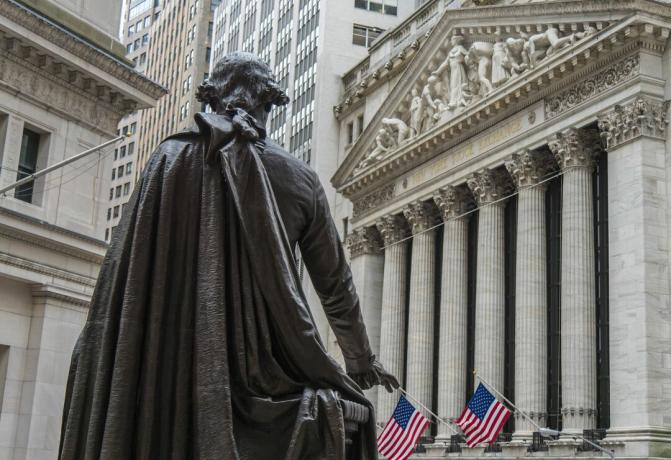 En statue af George Washington ser mod New York Stock Exchange-bygningen på Broad Street fra Federal Hall National Memorial på Wall Street i New York City.