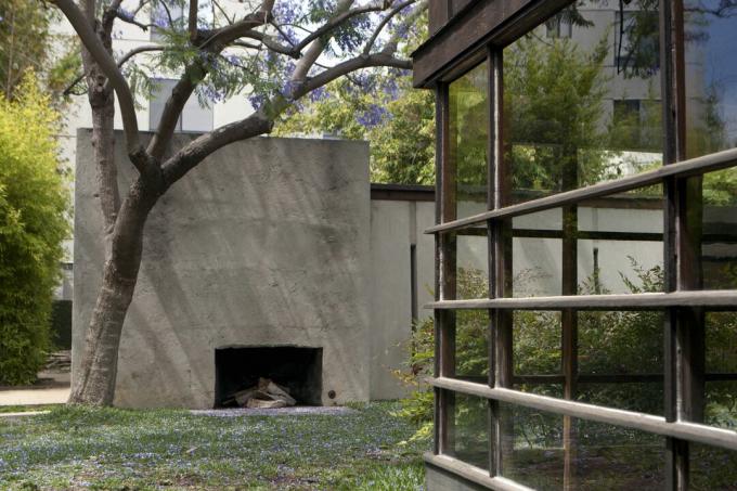 En udendørs pejs i en betonvæg overfor en væg med vinduer