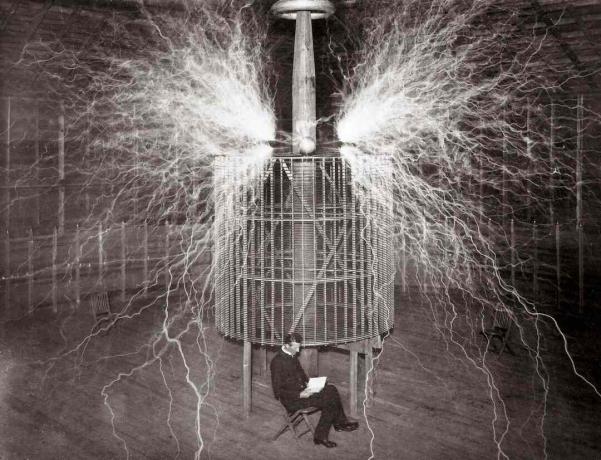Nikola Tesla sad i sit Colorado Springs laboratorium ved siden af ​​hans enorme 
