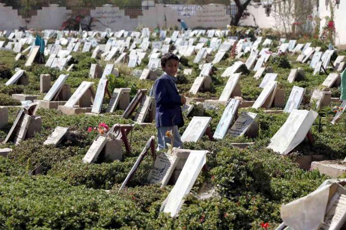 Et barn går blandt grave af mennesker, der blev dræbt i den igangværende krig på en kirkegård i Sana'a, Yemen.